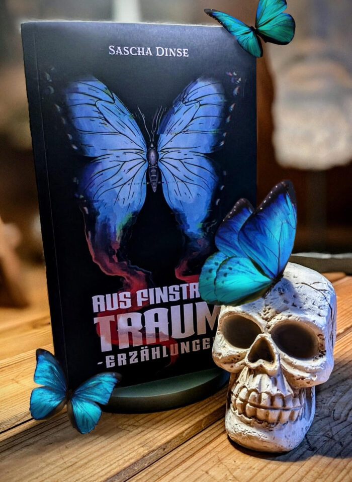 Sascha Dinse: Aus finstrem Traum - Erzählungen: Das Buch ist in schwarz gehalten, mit einem blauen Schmetterling im Cover. Vor dem Buch steht ein Totenschädel mit einem blauen Schmetterling darauf und zwei weitere sitzen am Buch.